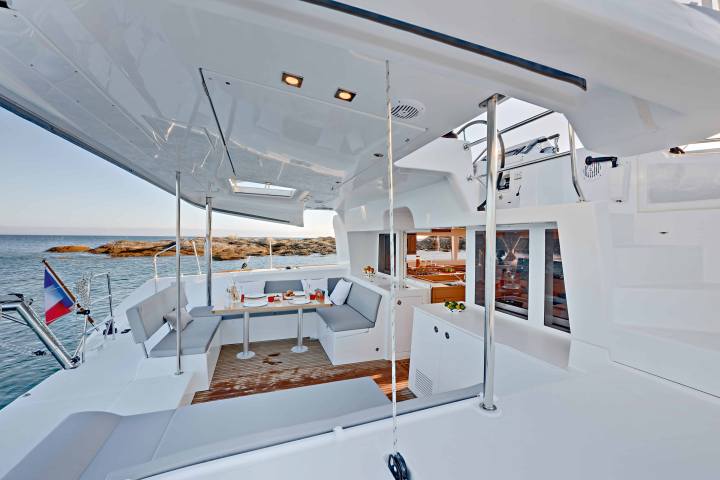 Luxury yacht deck with seating area, tables, and a sea view.