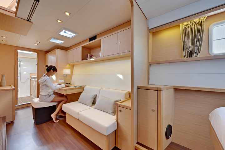 Person writing at a desk in a wooden interior room with couch and bathroom.