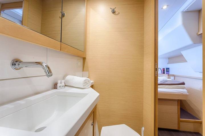 Compact bathroom with sink, towel, mirror, and view of adjacent bedroom with made bed.