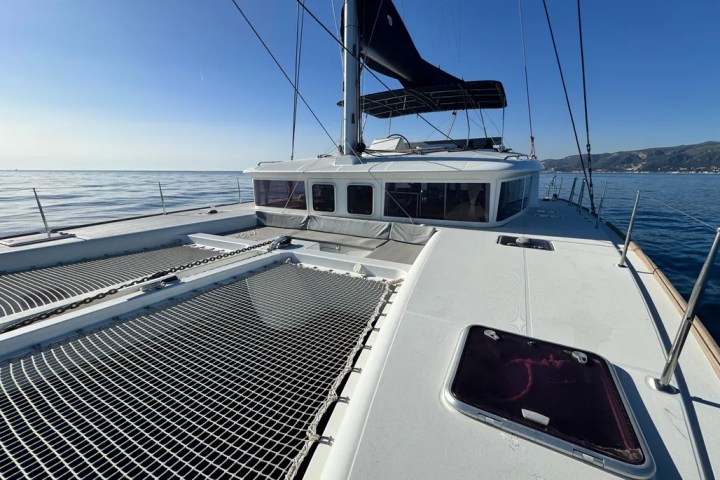 View from the deck of a catamaran with blue sky and ocean in background.