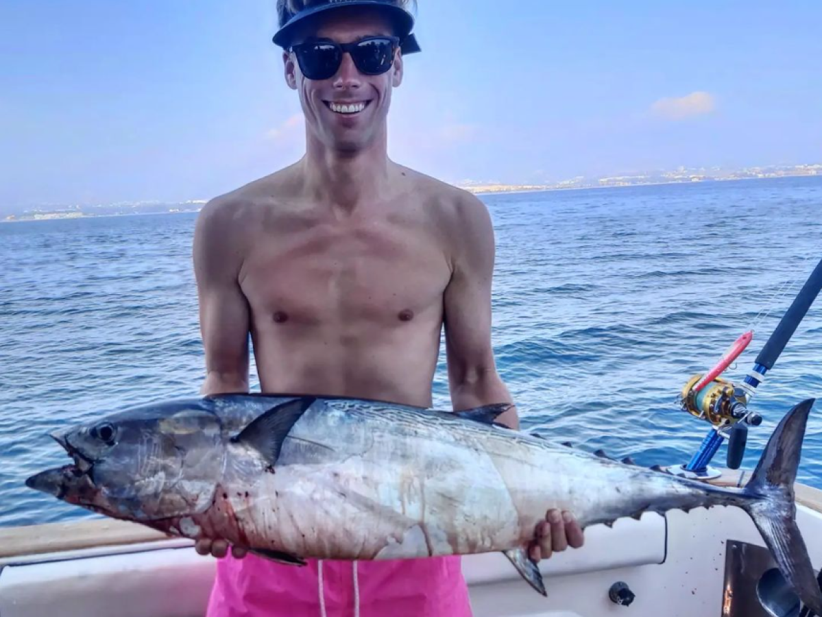 a man holding a fish on a boat in the water