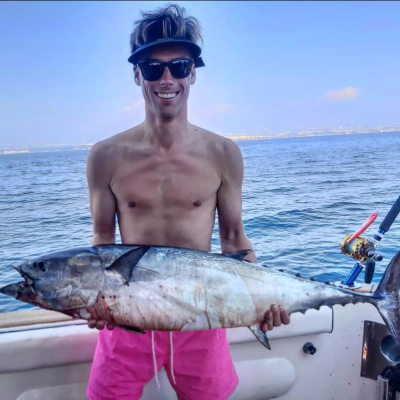 a man holding a fish on a boat in the water