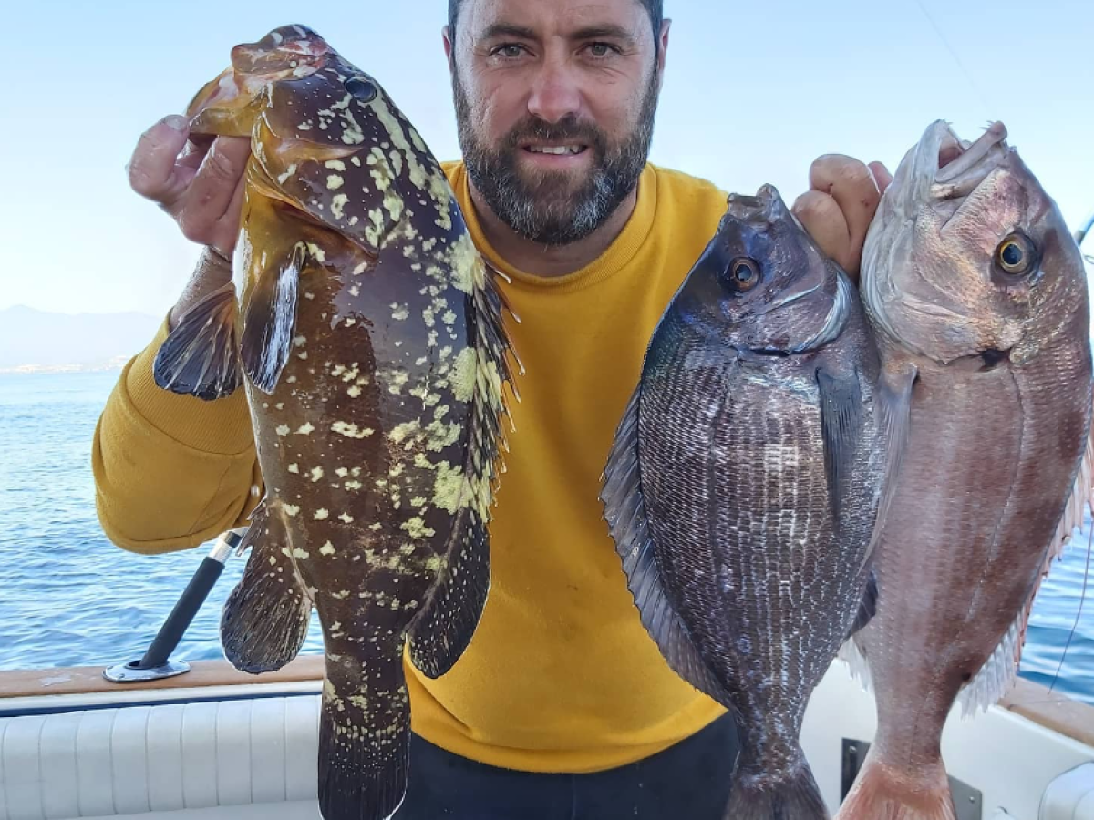 a man holding a fish posing for the camera
