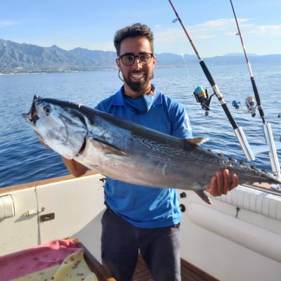 a man holding a fish on a boat in the water