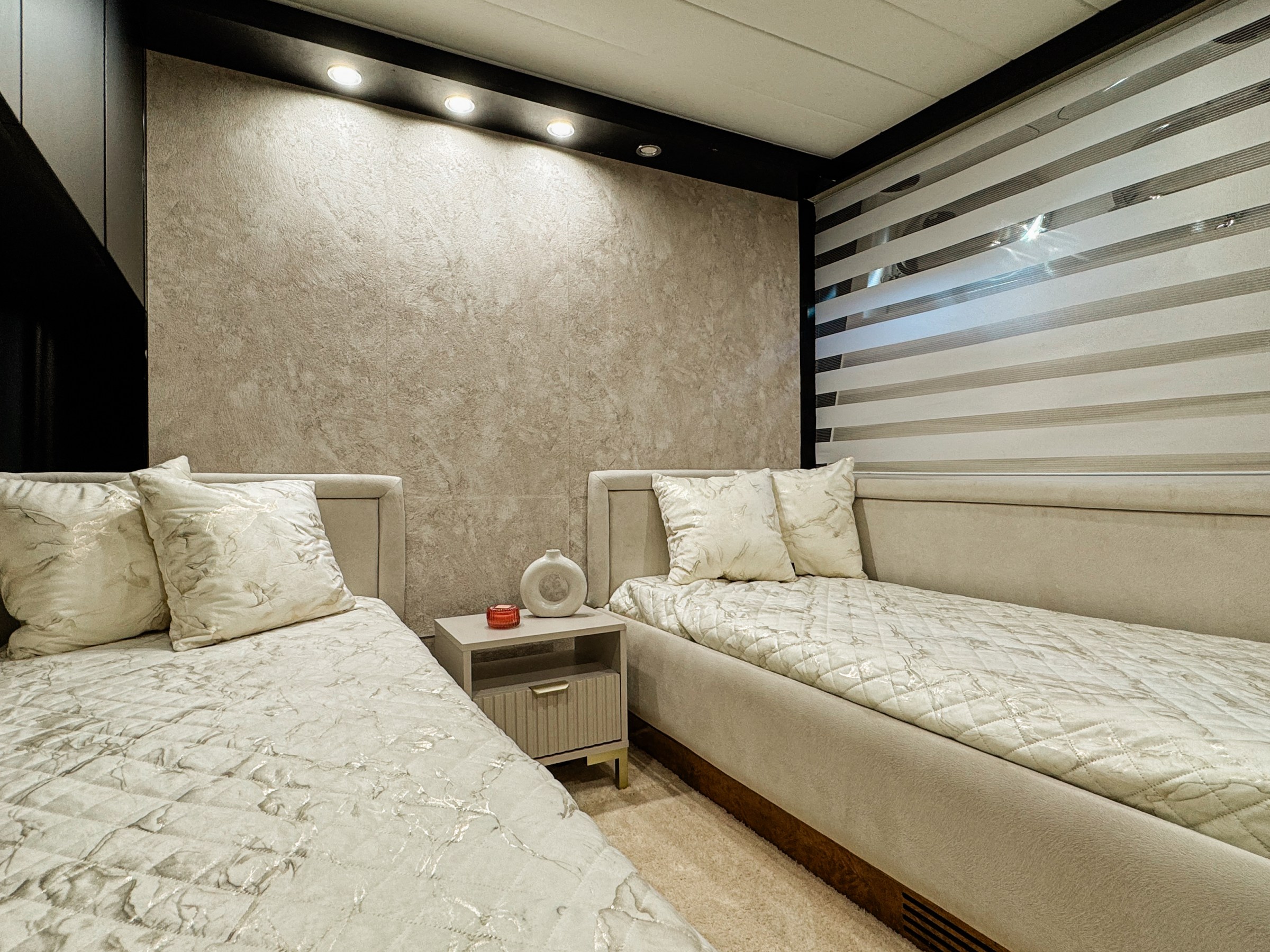 Modern bedroom with two single beds, neutral tones, and decorative pillows.