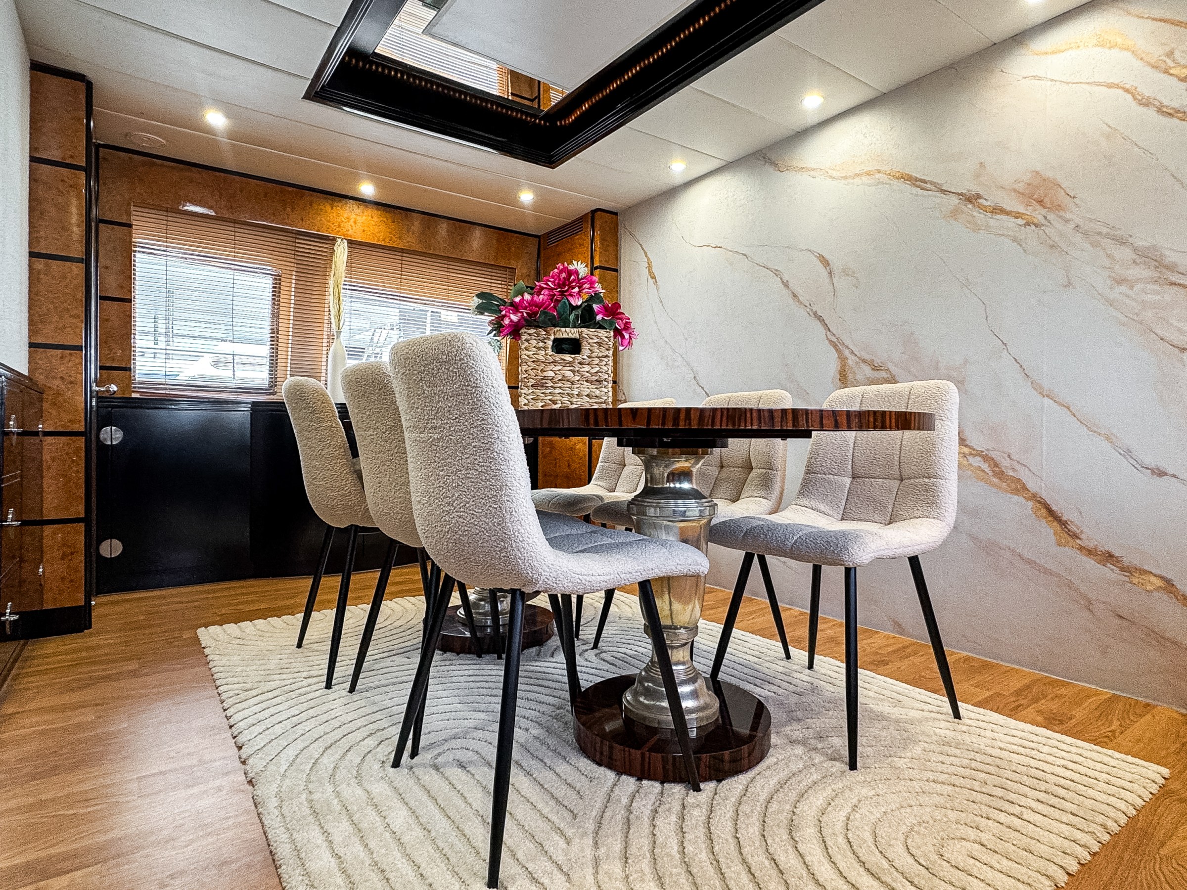 Elegant dining room with modern chairs, wooden table, and marble accent wall.