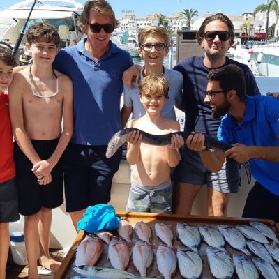 Group of people on a boat displaying a large catch of fish