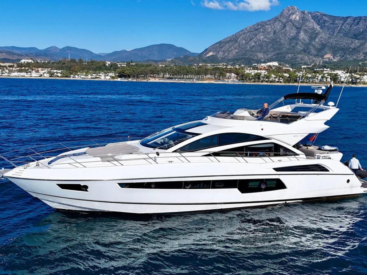Luxury yacht sailing on blue sea with mountains in background.