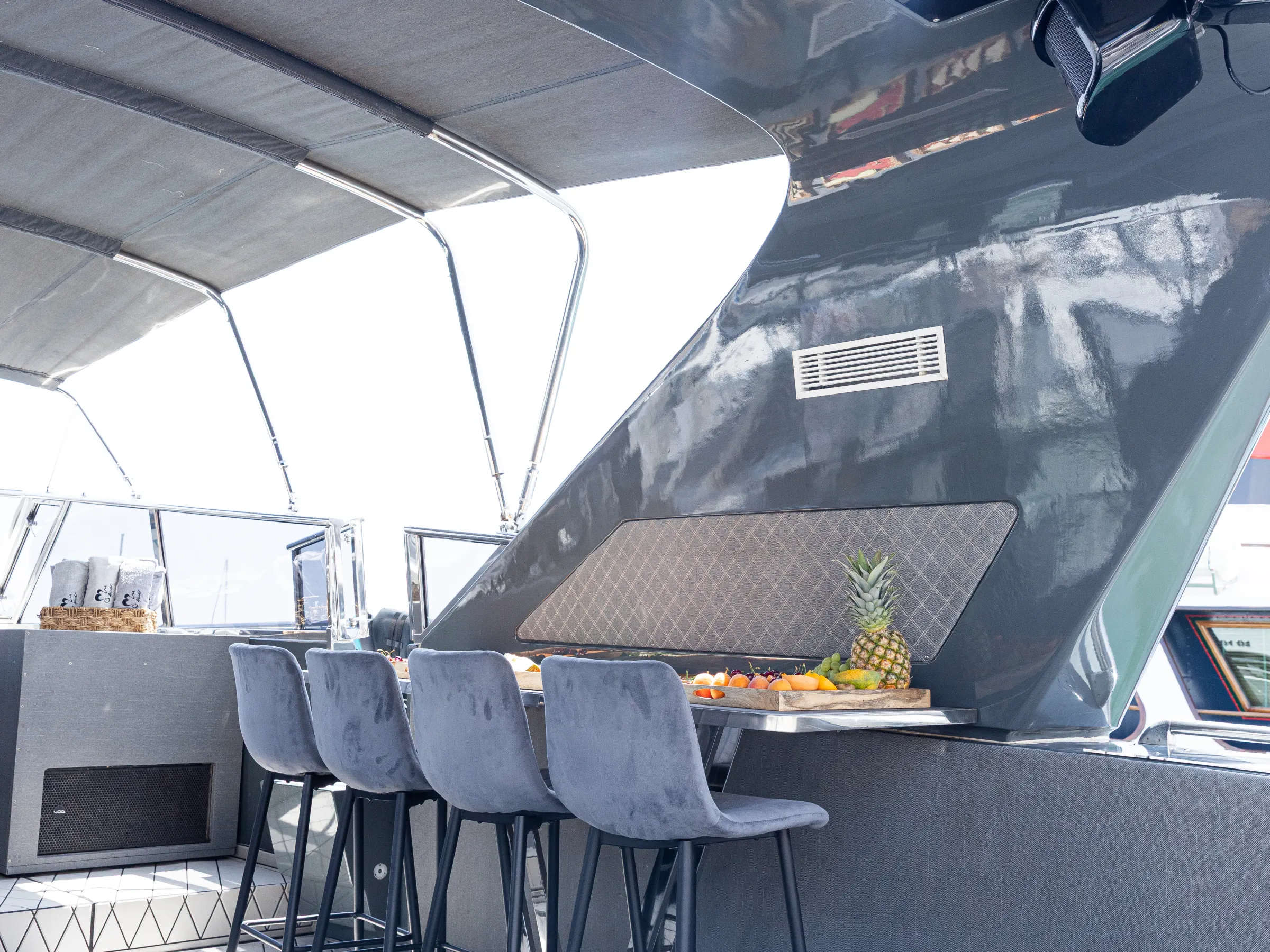 Luxurious yacht interior with bar stools, countertop, and fruit platter.