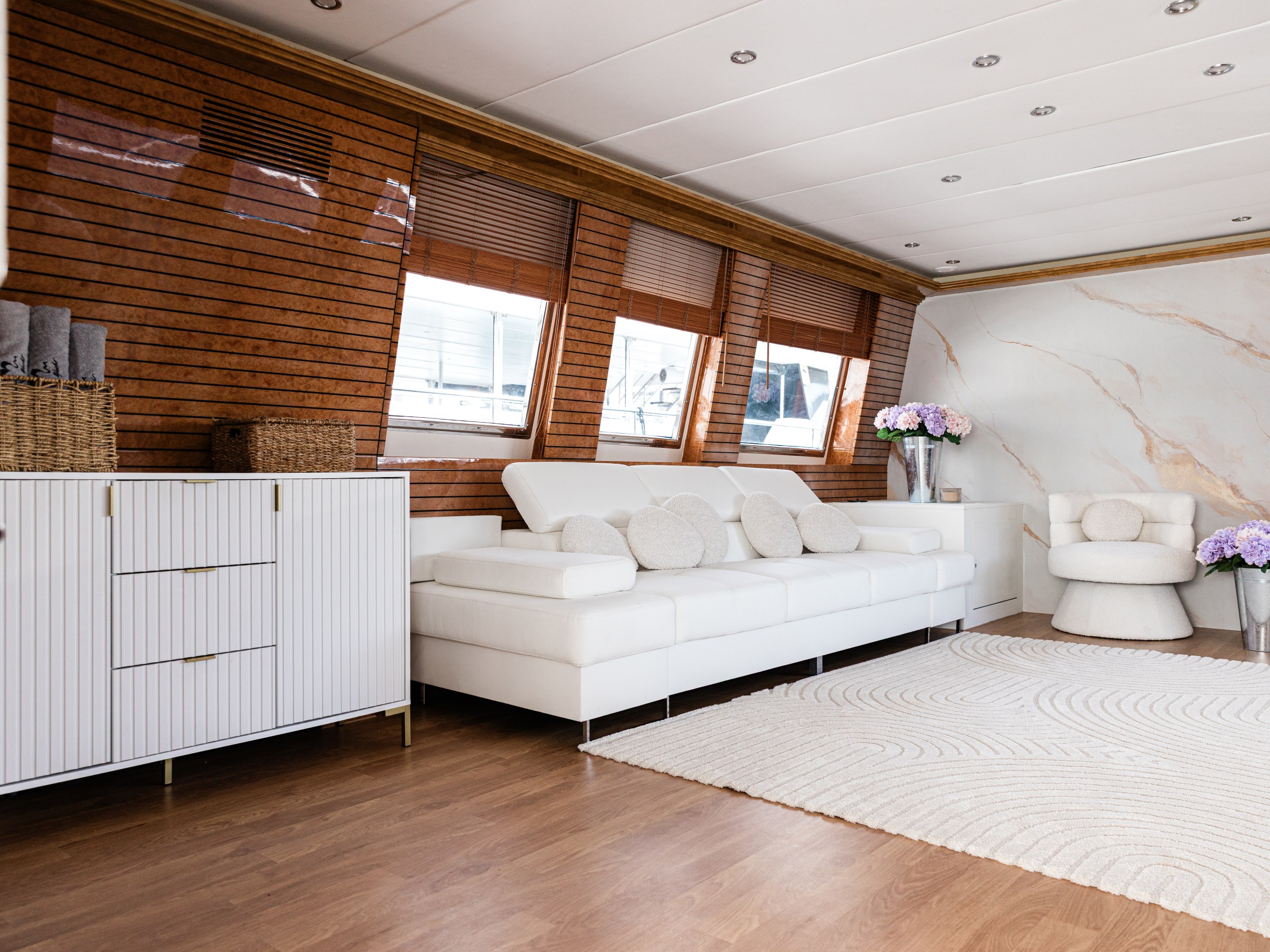 Modern living room with white sofa, wood paneling, and marble wall.