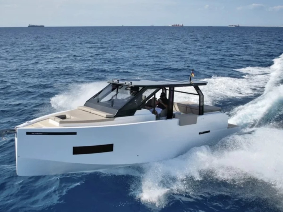 A sleek white motorboat speeding on the ocean, leaving a trail of waves behind it.