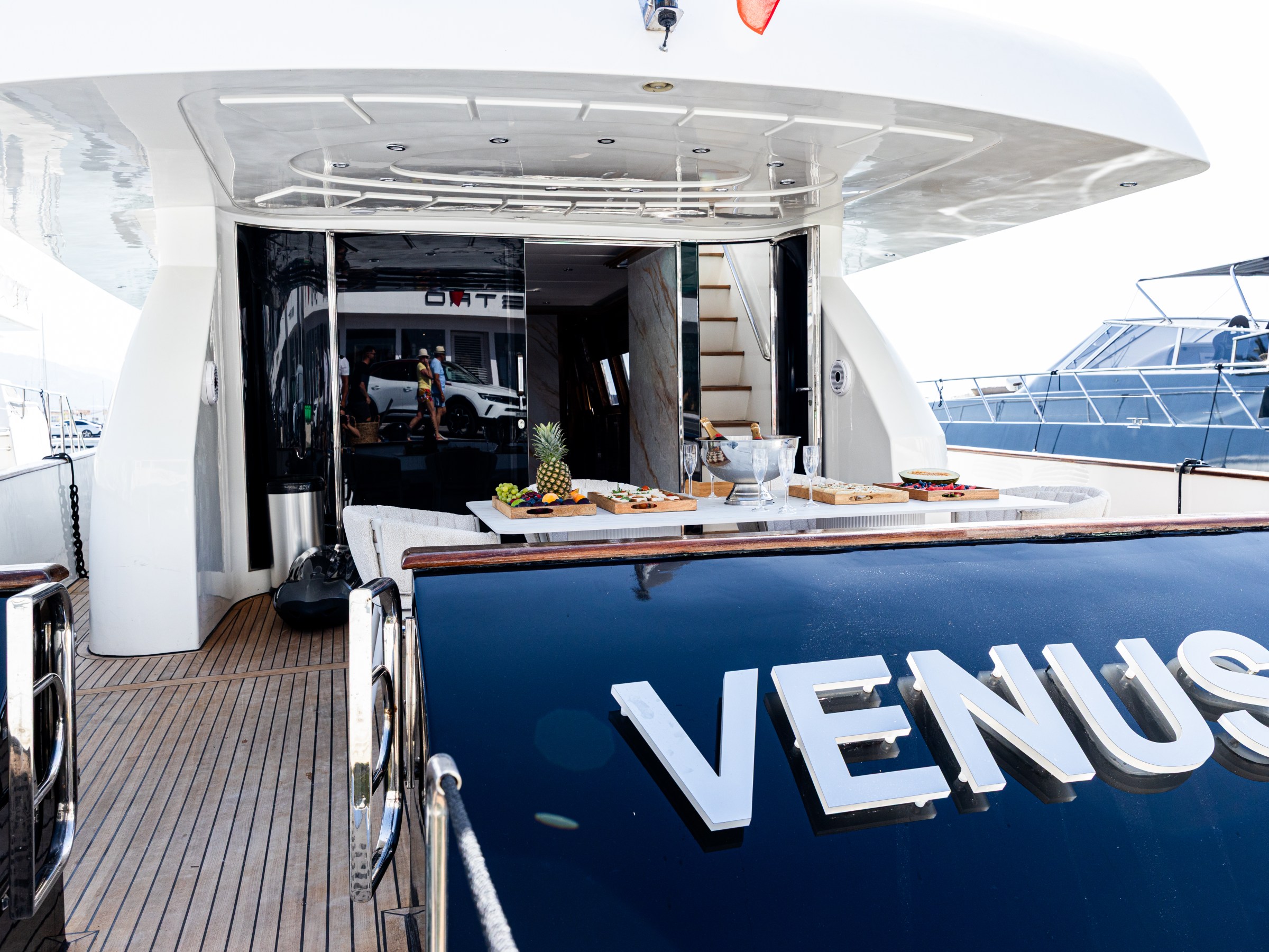 The rear deck of a yacht named 'VENUS' with a table set for dining.