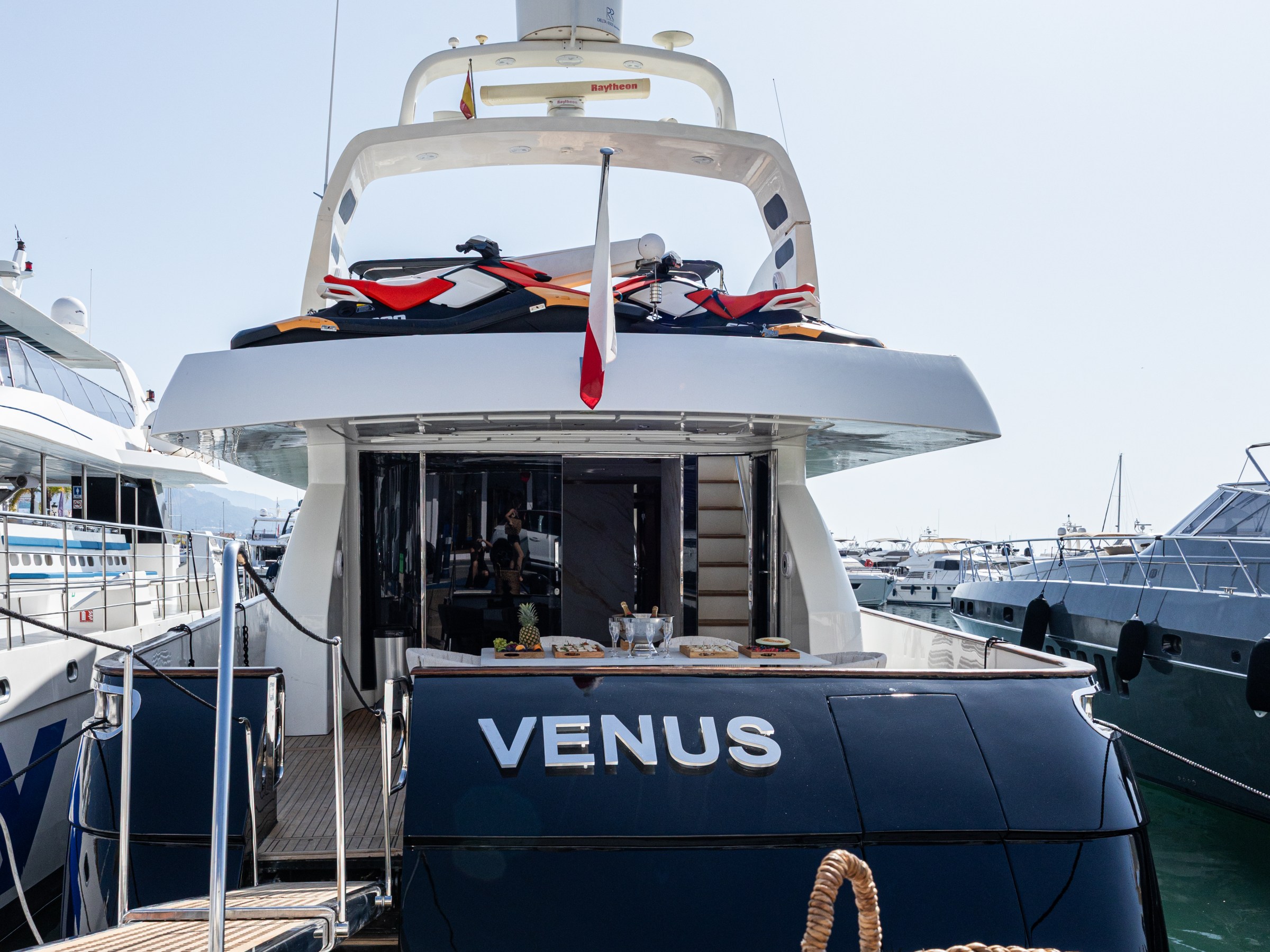 Rear view of a yacht named 'Venus' docked at a marina on a sunny day.