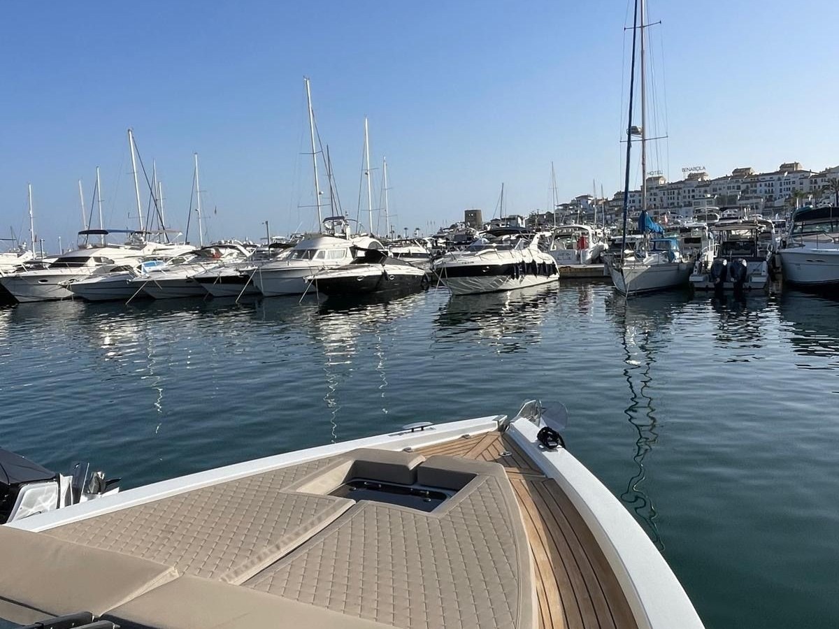 View from a yacht's deck in a marina with multiple boats and a clear blue sky.