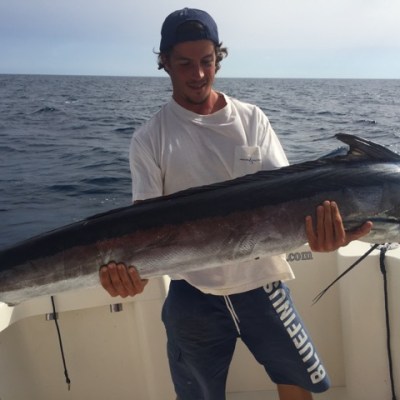 Person on boat holding a large fish with the ocean in the background.