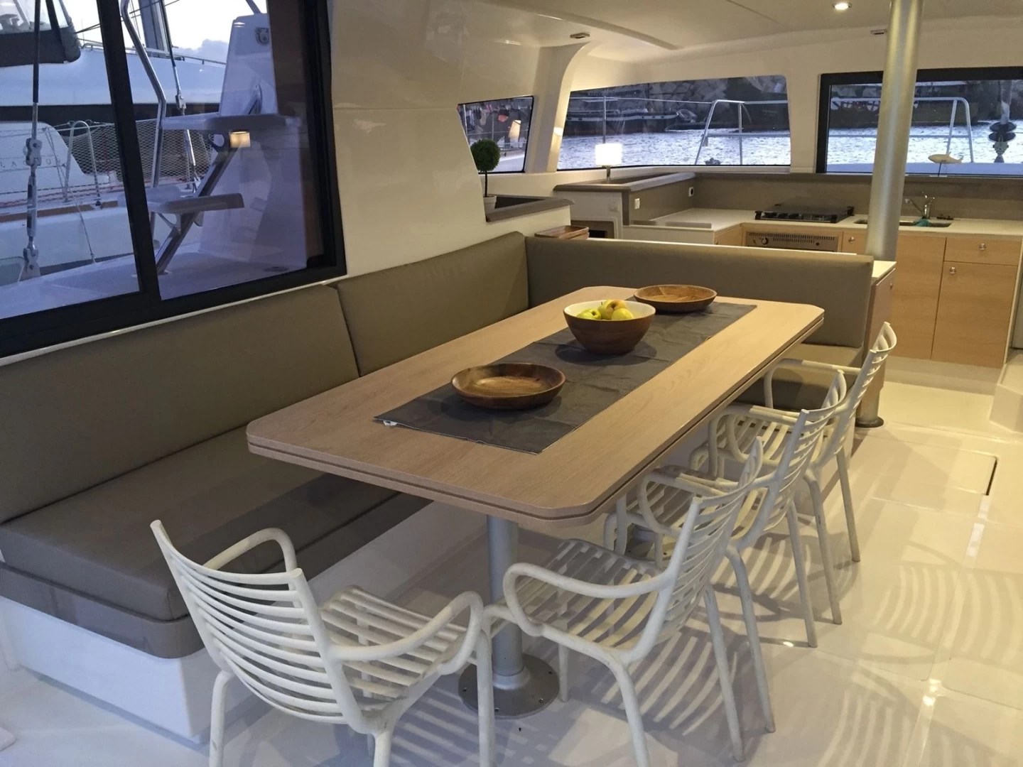 Boat interior with a dining table, chairs, and kitchen area.