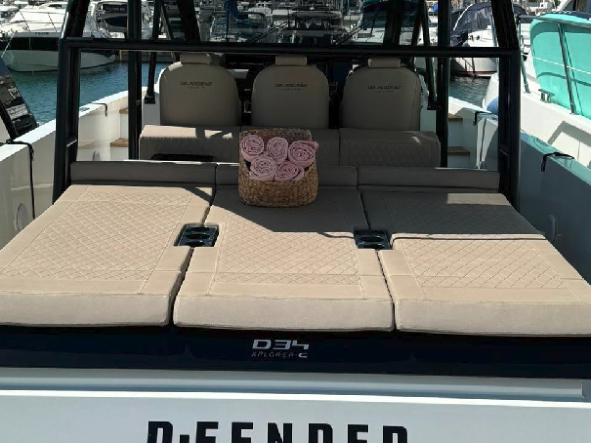 Back view of a boat's seating area with beige cushions and a basket of pink roses.