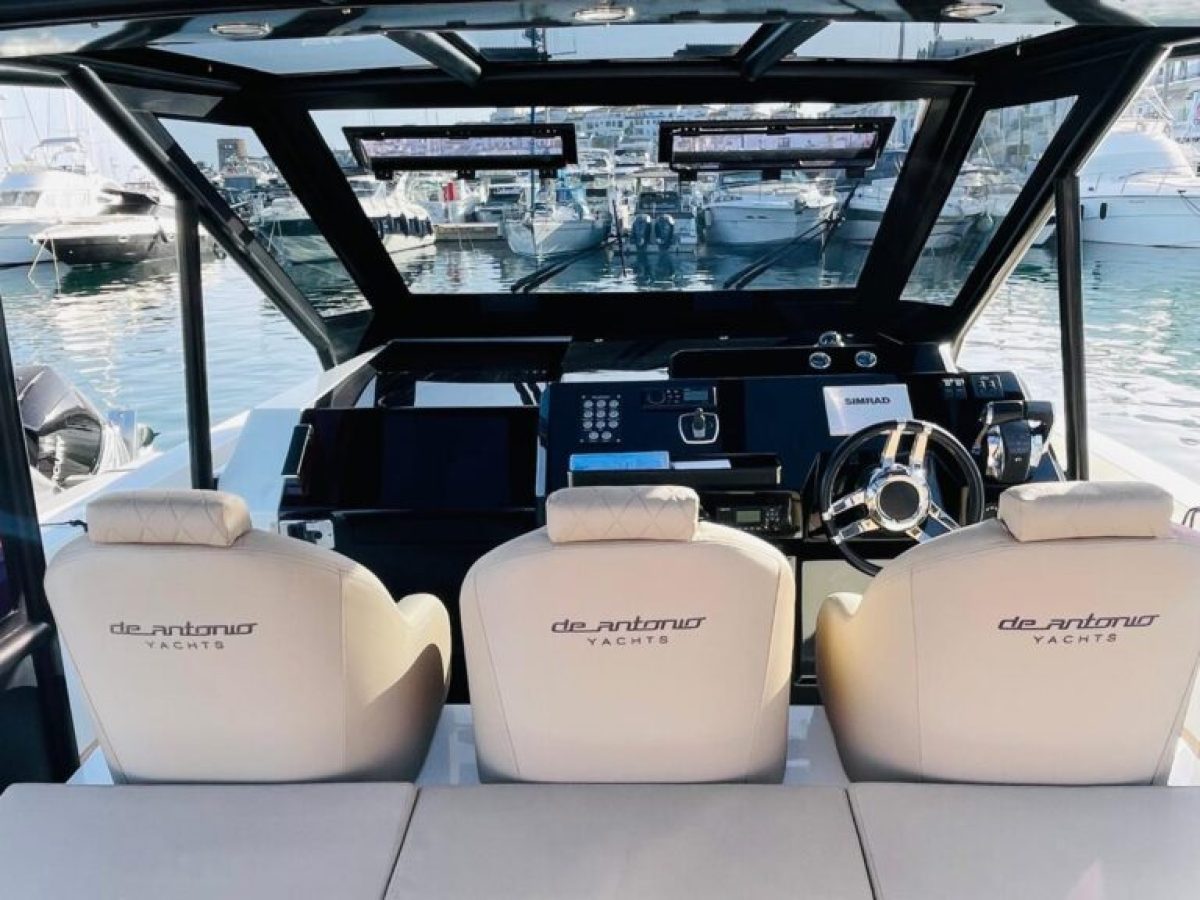 Interior view of a yacht's cockpit with a panoramic marina view.