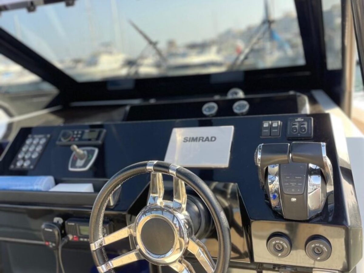 Boat cockpit with steering wheel, control panel, and Simrad screen.