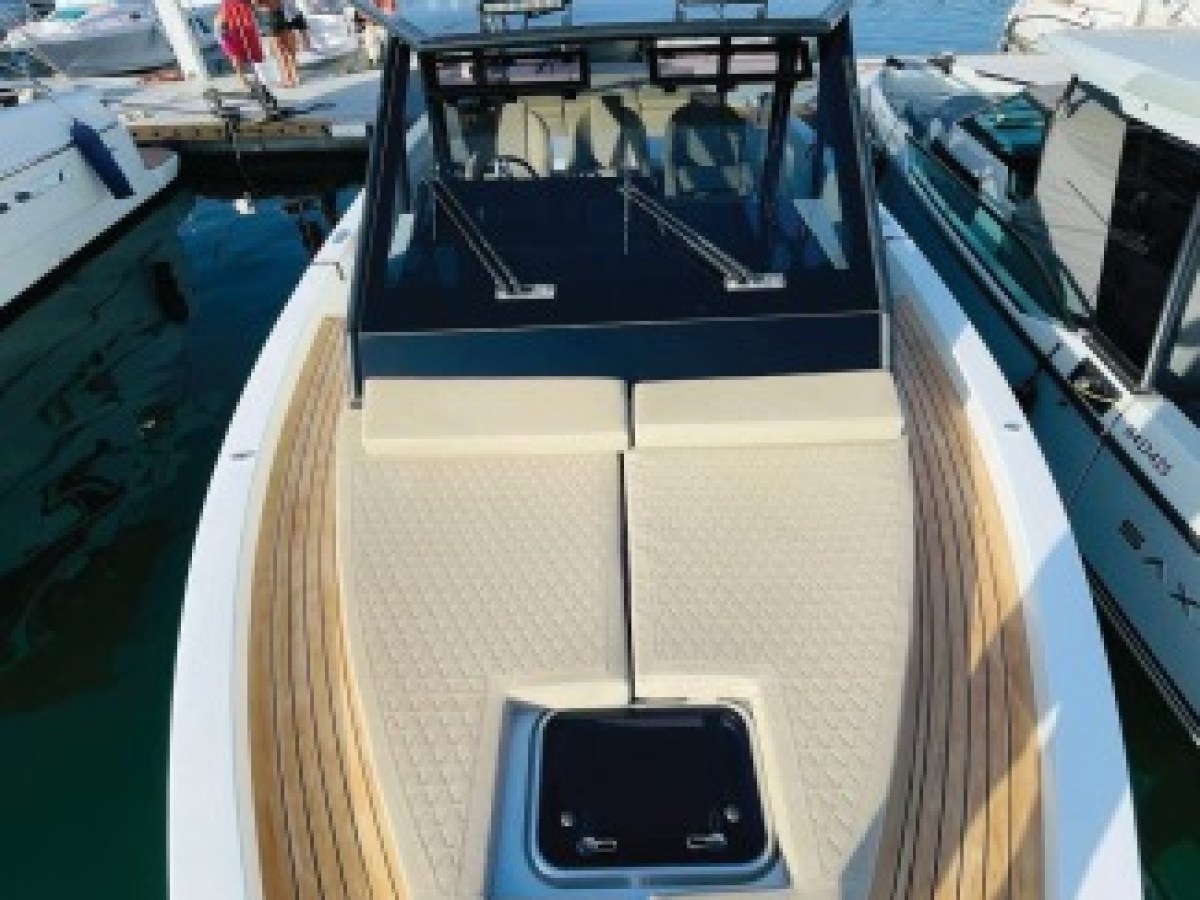 Modern motorboat docked in a marina with white buildings and blue sky.