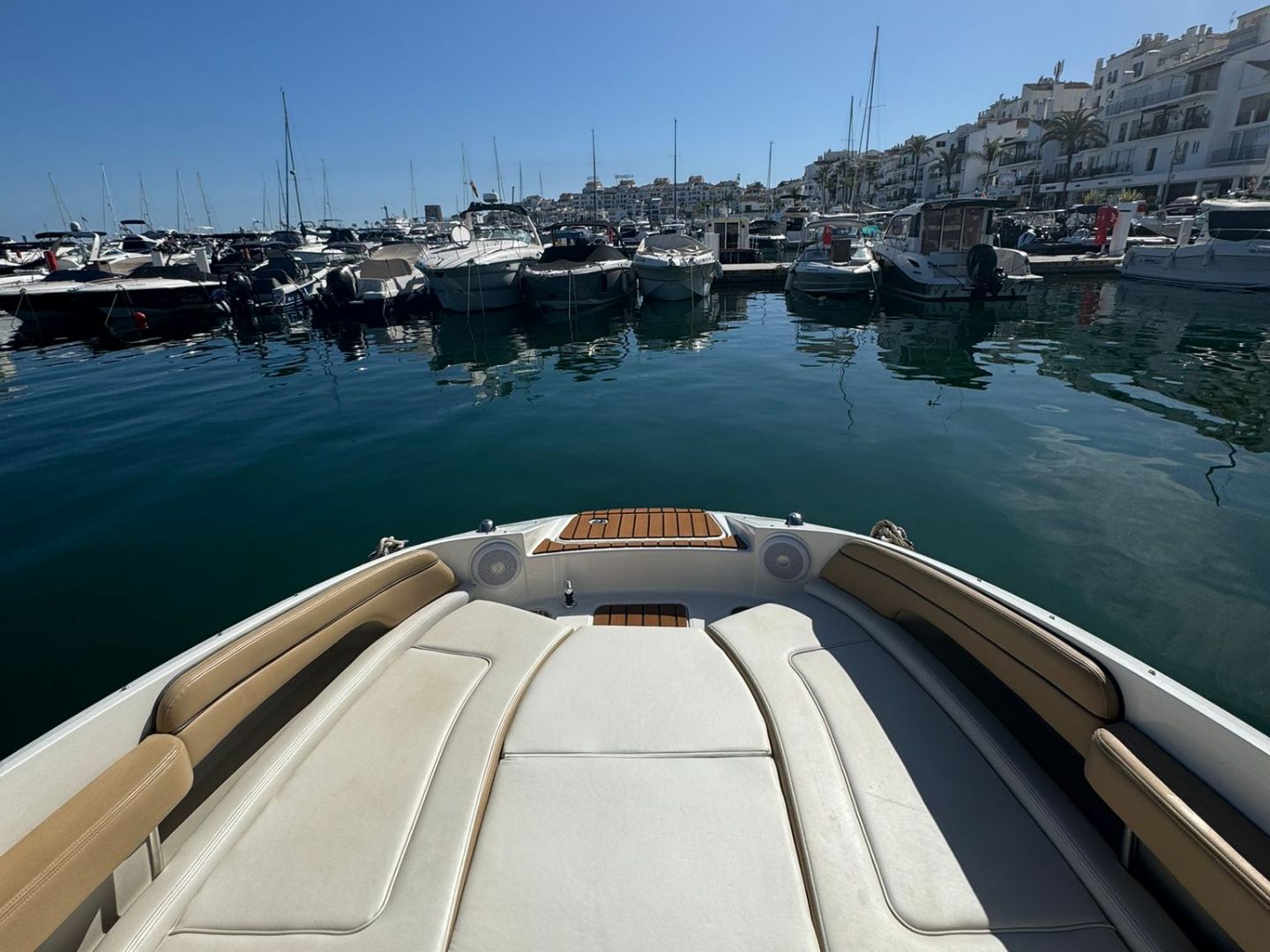 View from a boat's deck towards a marina with docked boats under a clear blue sky.