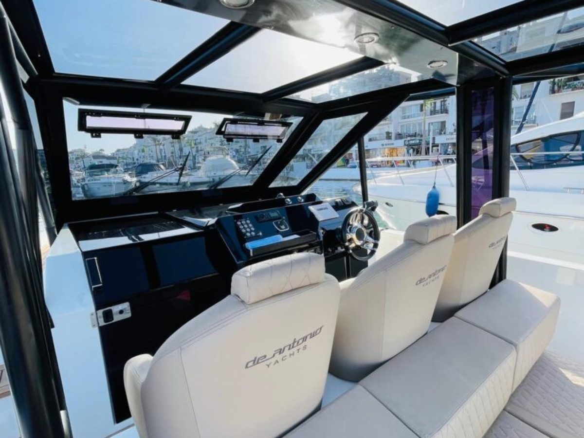 Interior view of luxury yacht cockpit with two seats and steering wheel facing marina.
