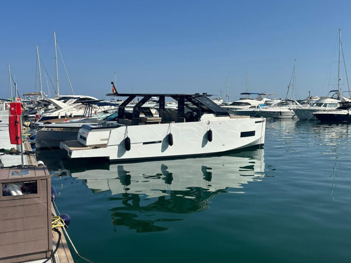 A white motorboat docked in a marina with several boats in the background.