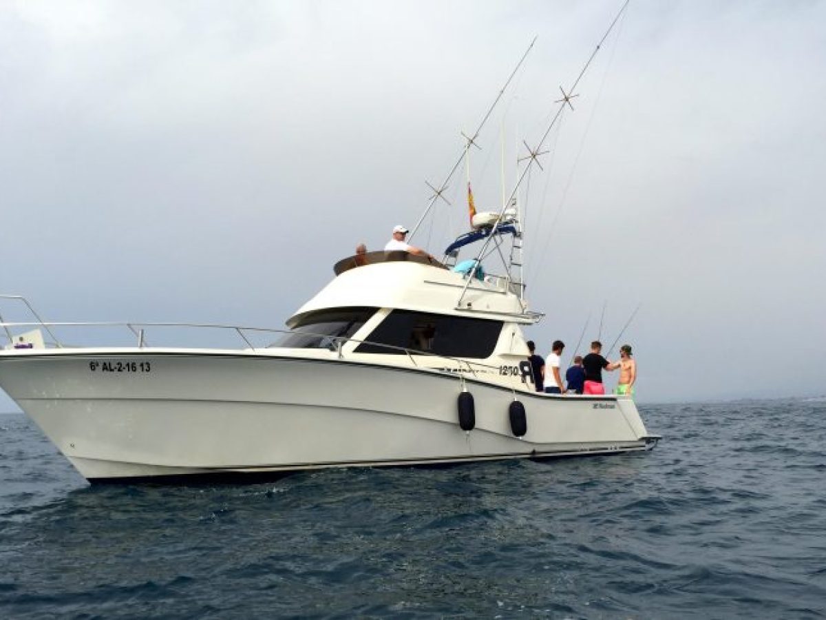 People on a white yacht fishing in the open sea under a cloudy sky.