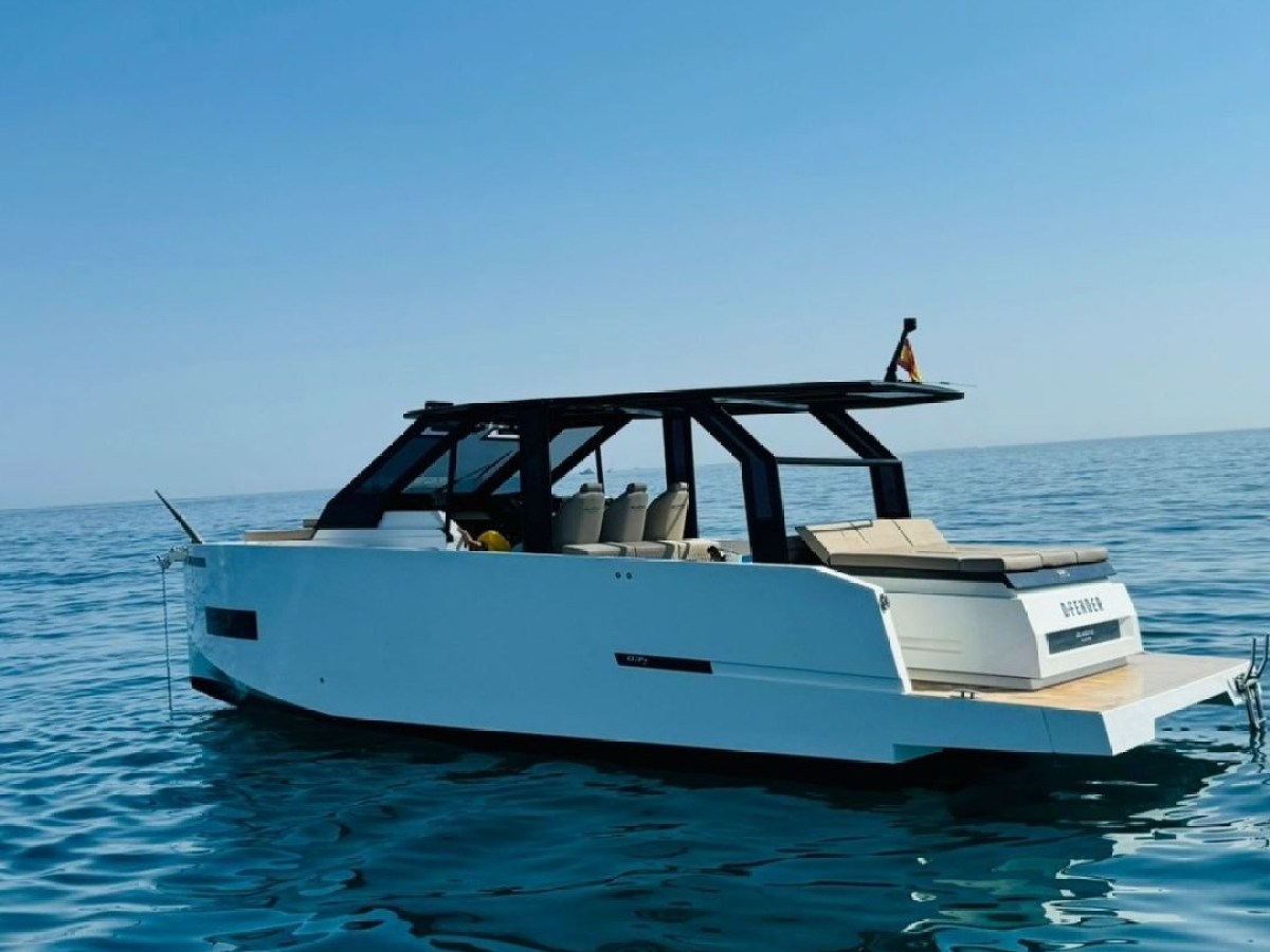 Modern white yacht floating on calm blue sea under clear sky.