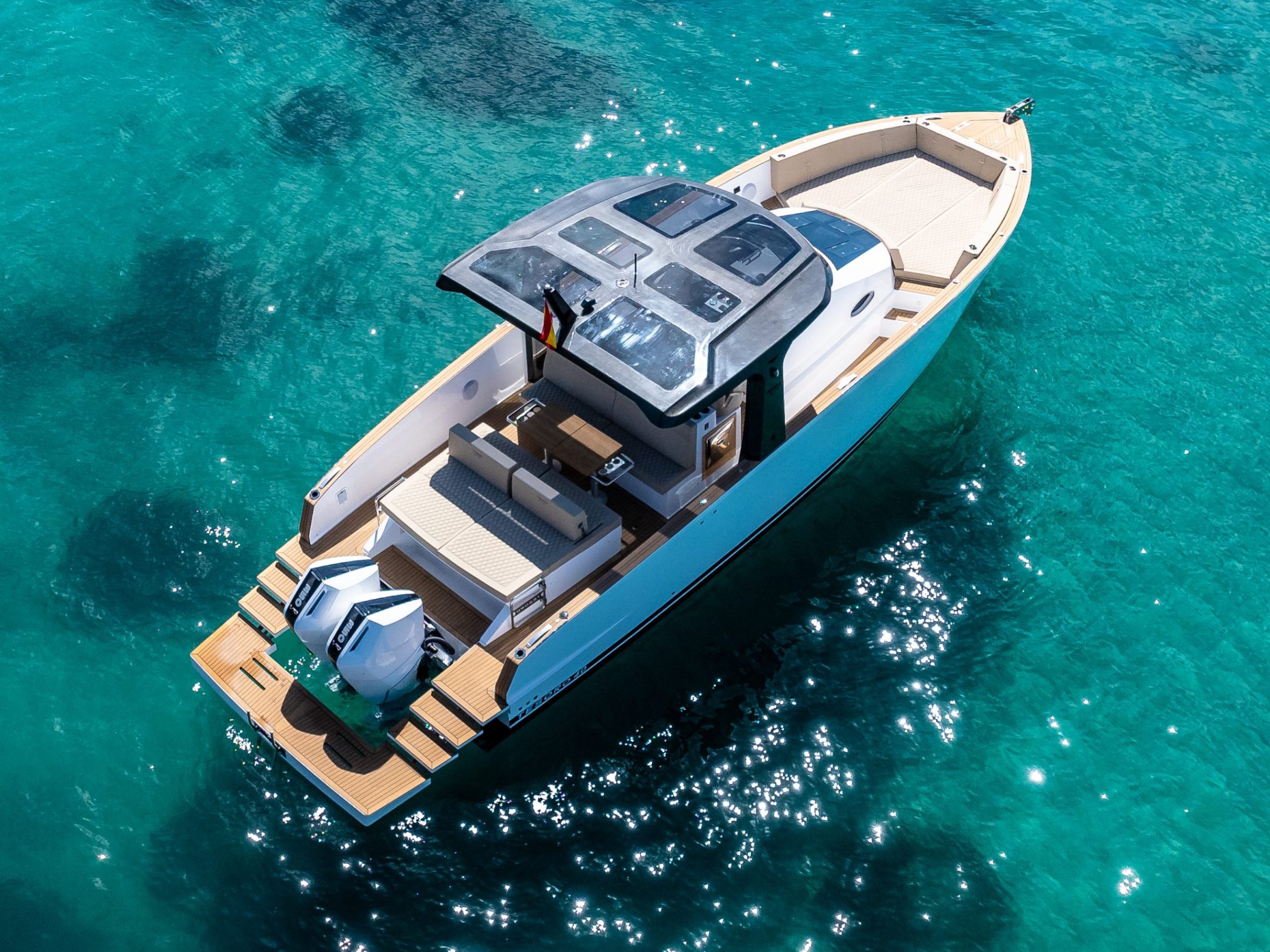Aerial view of a motorboat with a canopy on clear turquoise water.