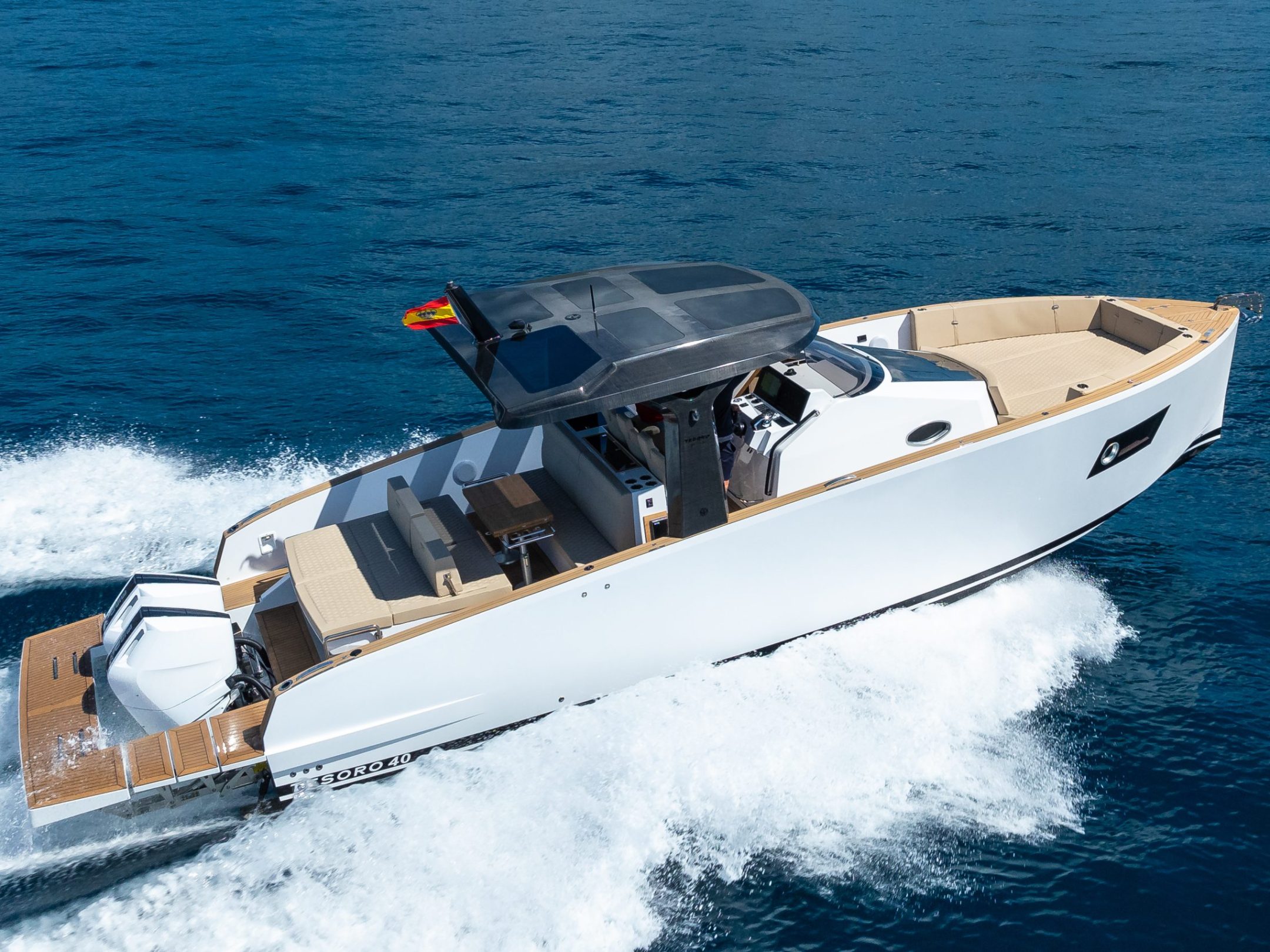 A white motorboat with a dark roof speeding across blue water.