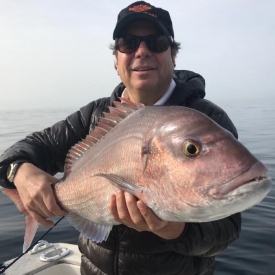 Person holding a large fish while standing on a boat in open water.