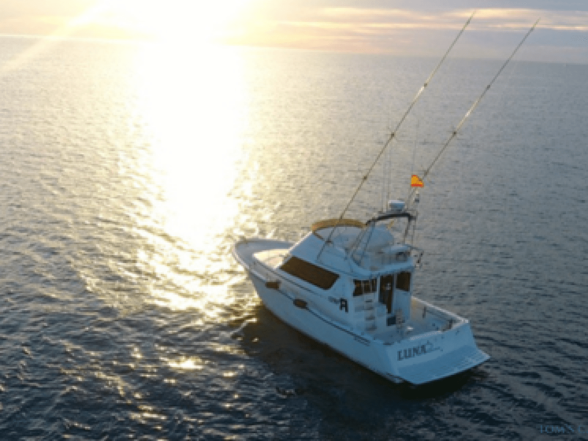 A boat on the ocean with sunset glow reflecting on the water.