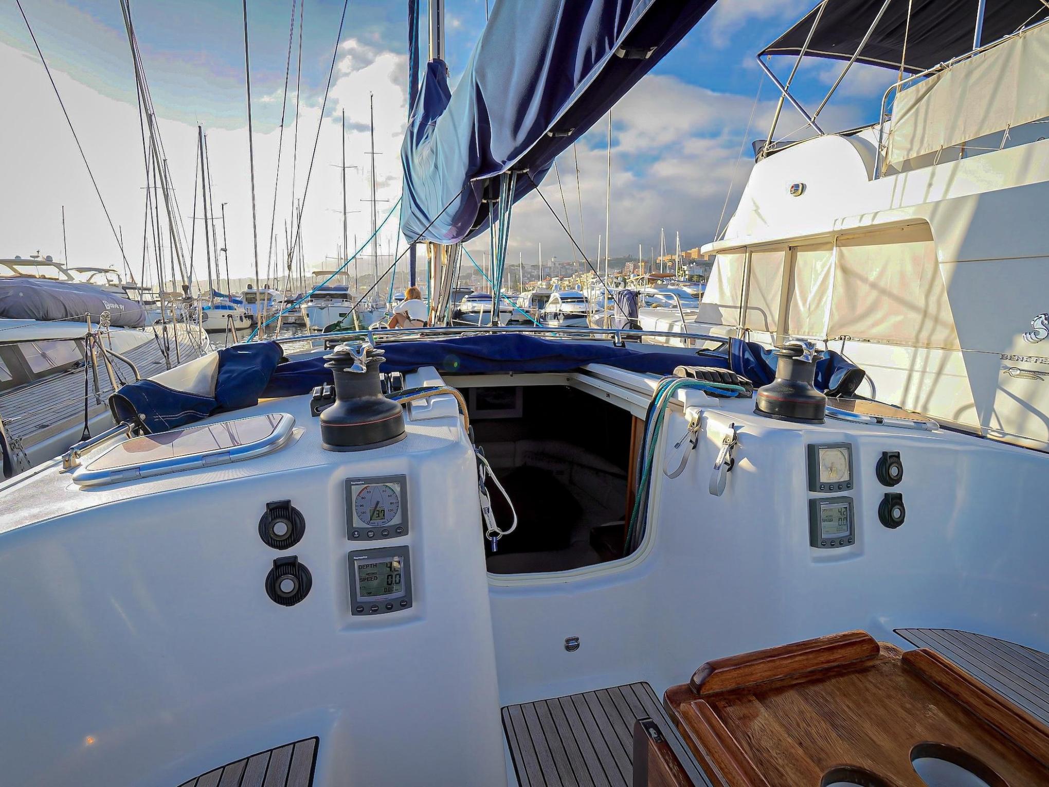 View of a sailboat cockpit with instruments and marina in the background.