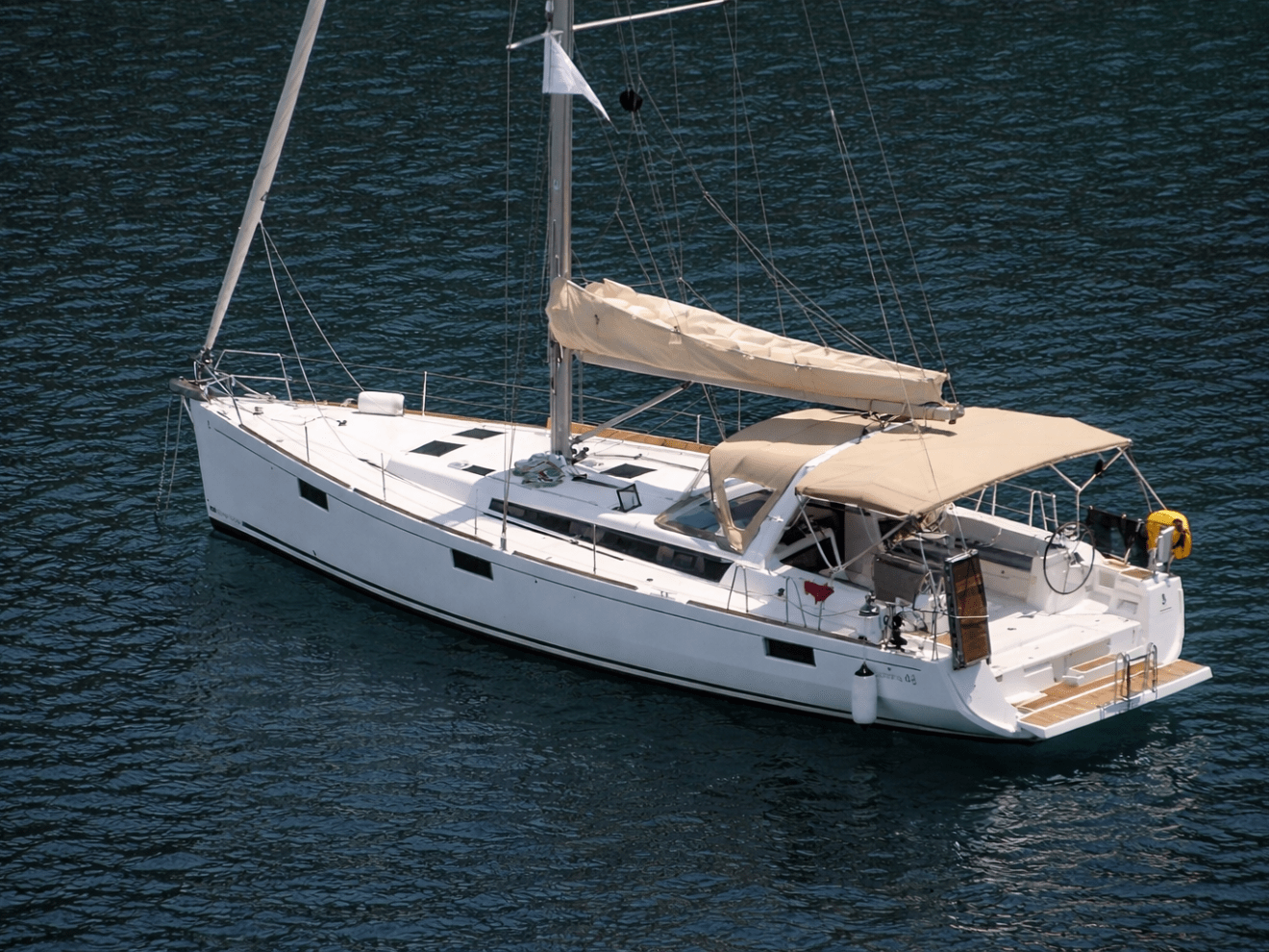 White sailboat with beige canopy on blue water.