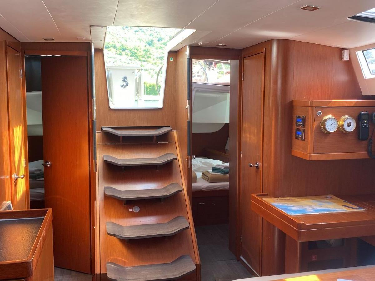 Interior of a boat cabin with wooden walls, stairs, and a skylight.