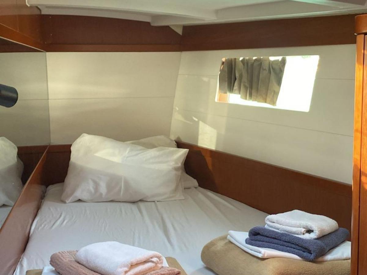 Boat cabin with a neatly made bed and folded towels.
