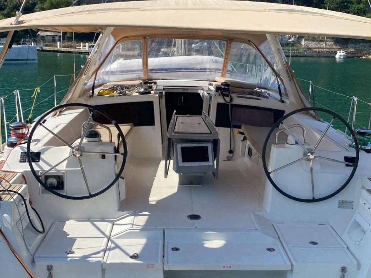 Sailboat cockpit with twin steering wheels and hilly background.