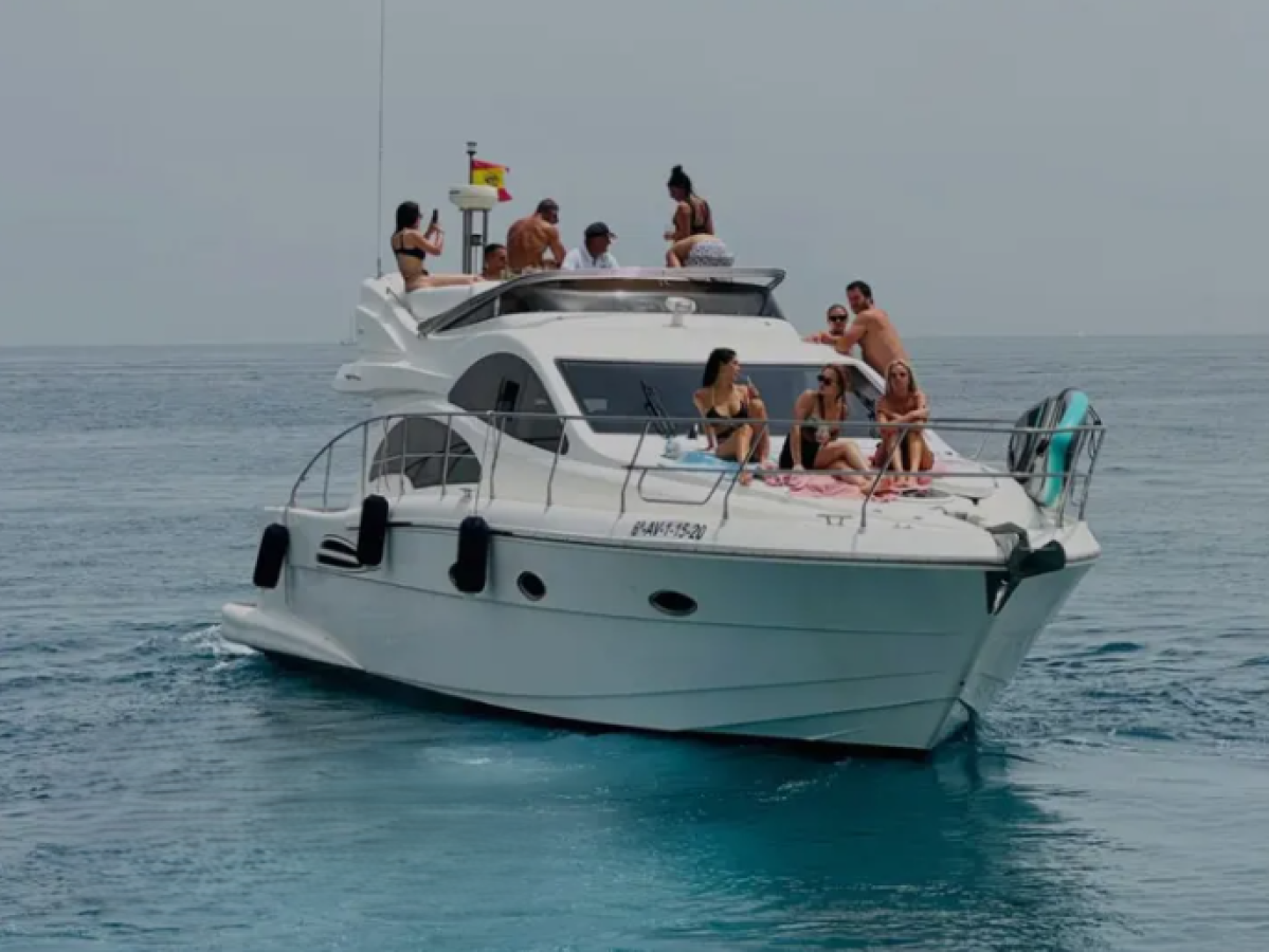 People relaxing on a white yacht at sea under a clear sky.