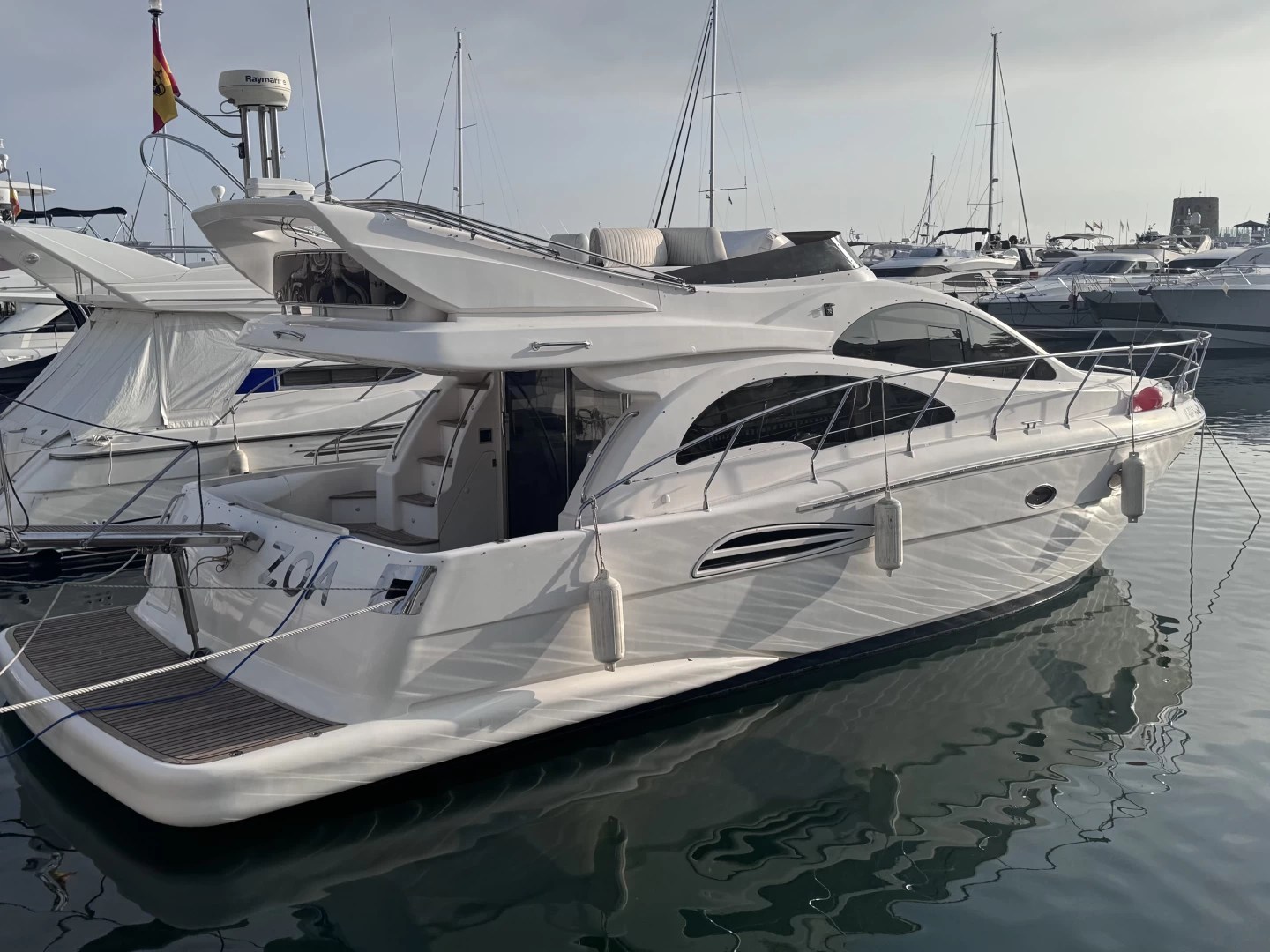 White yacht docked in marina with other boats.
