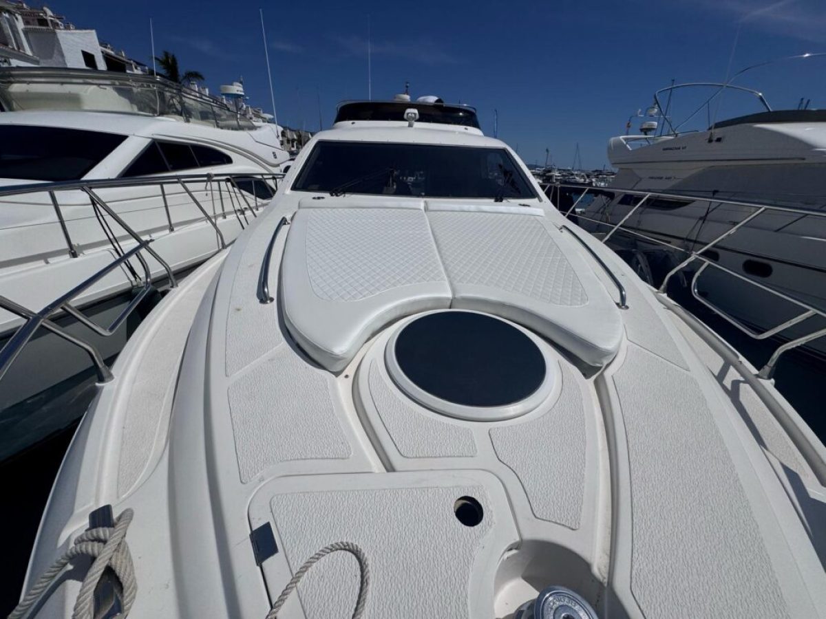 Front view of a white luxury yacht decked at a marina.