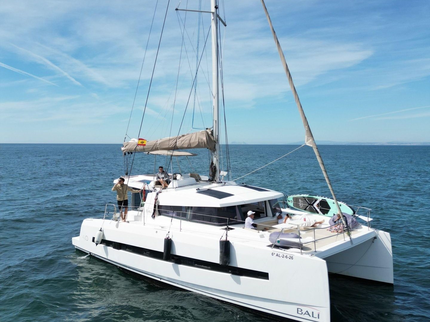 White catamaran sailing on calm ocean under clear blue sky.
