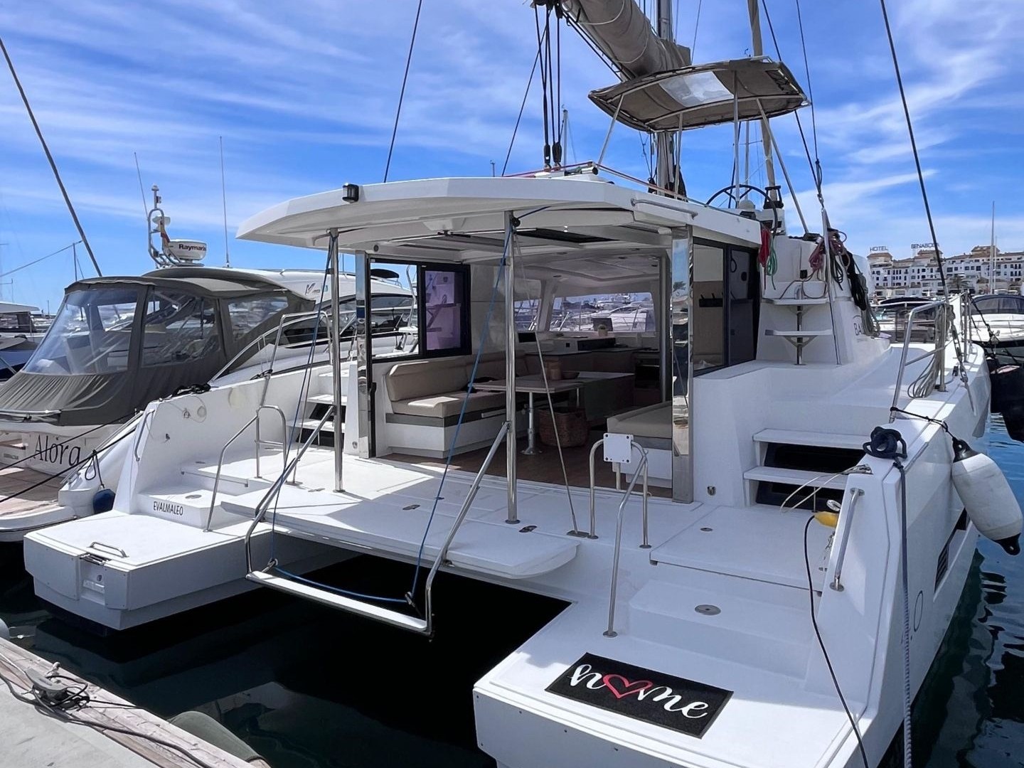 A white catamaran docked at a marina under a blue sky.
