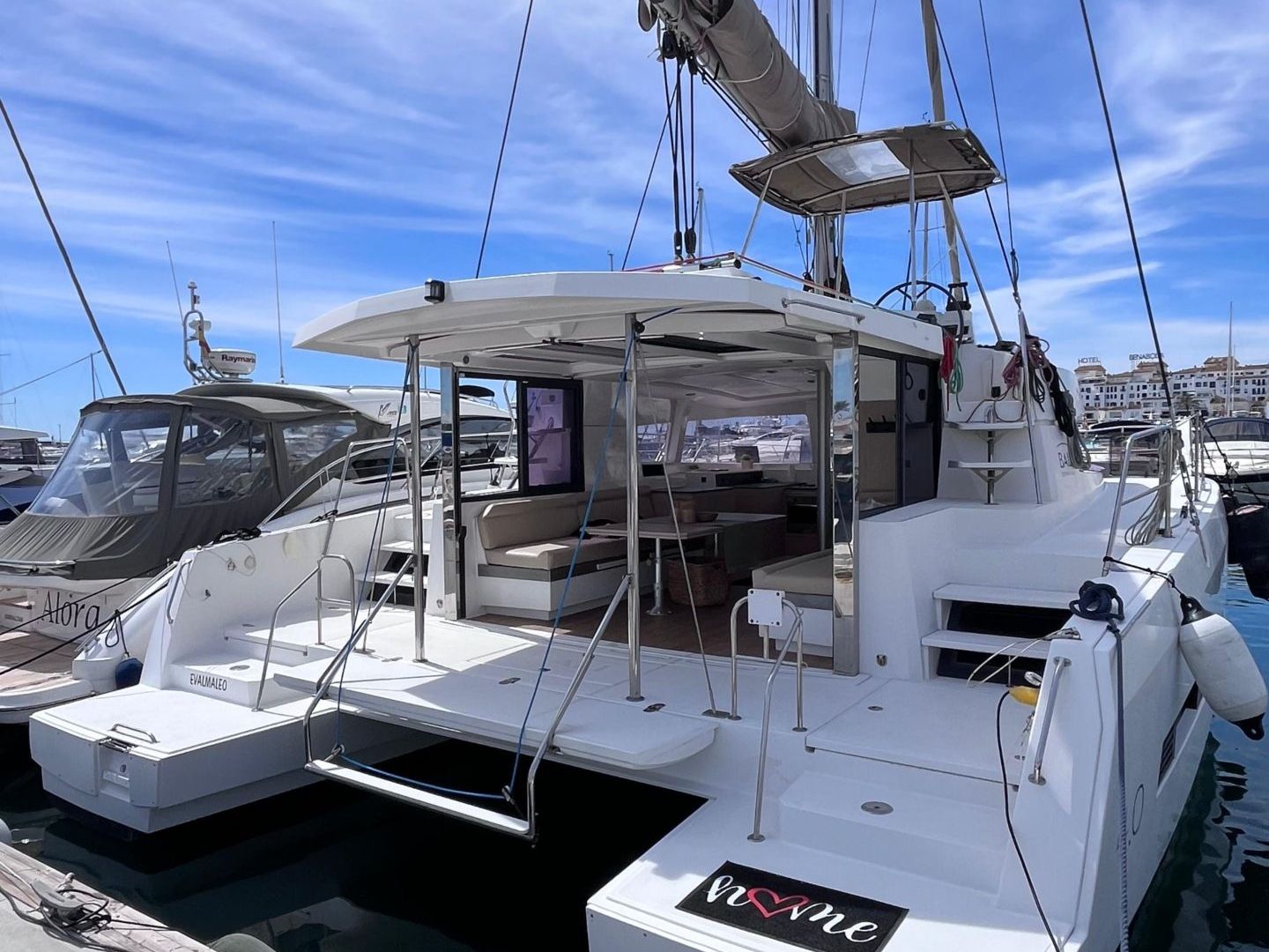 White catamaran yacht docked at a marina under a blue sky.