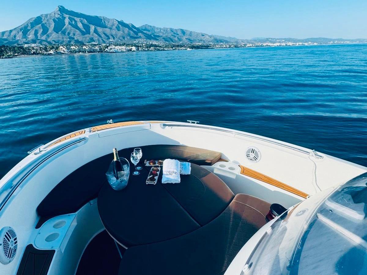 Boat deck with snacks and drinks on open water, mountain view.