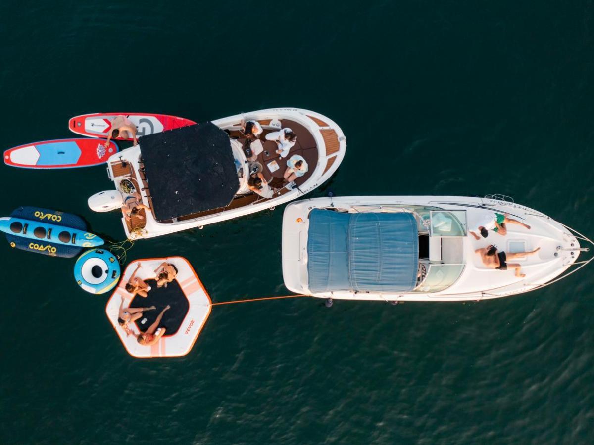 Top view of two boats and inflatables on dark water with people relaxing.