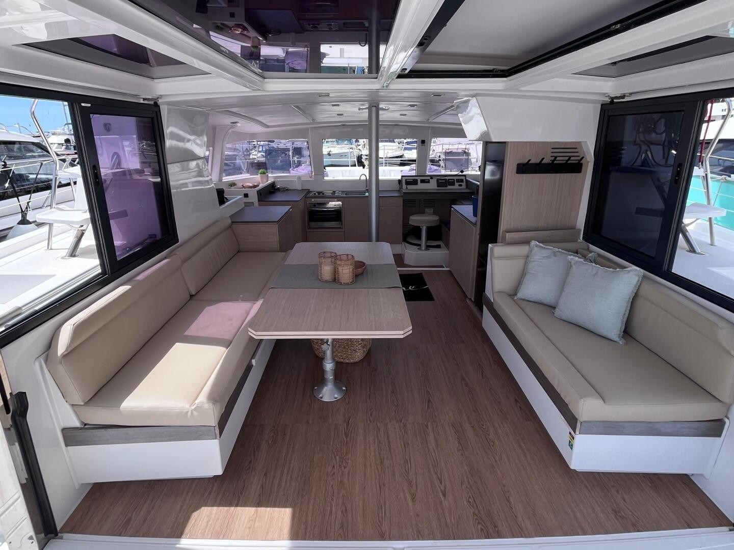 Spacious yacht interior with seating, table, and windows overlooking a marina.