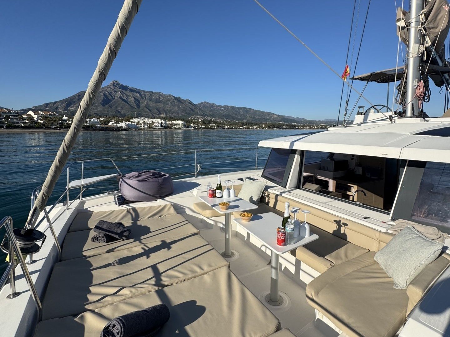 Catamaran deck with seating, snacks, and mountain view.