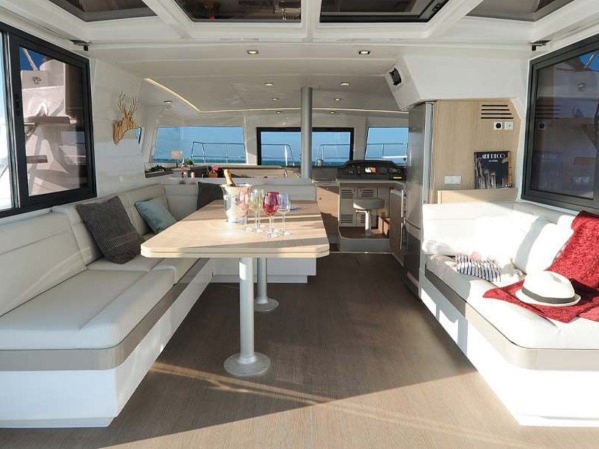 Interior of a yacht with seating, table, and red blanket.
