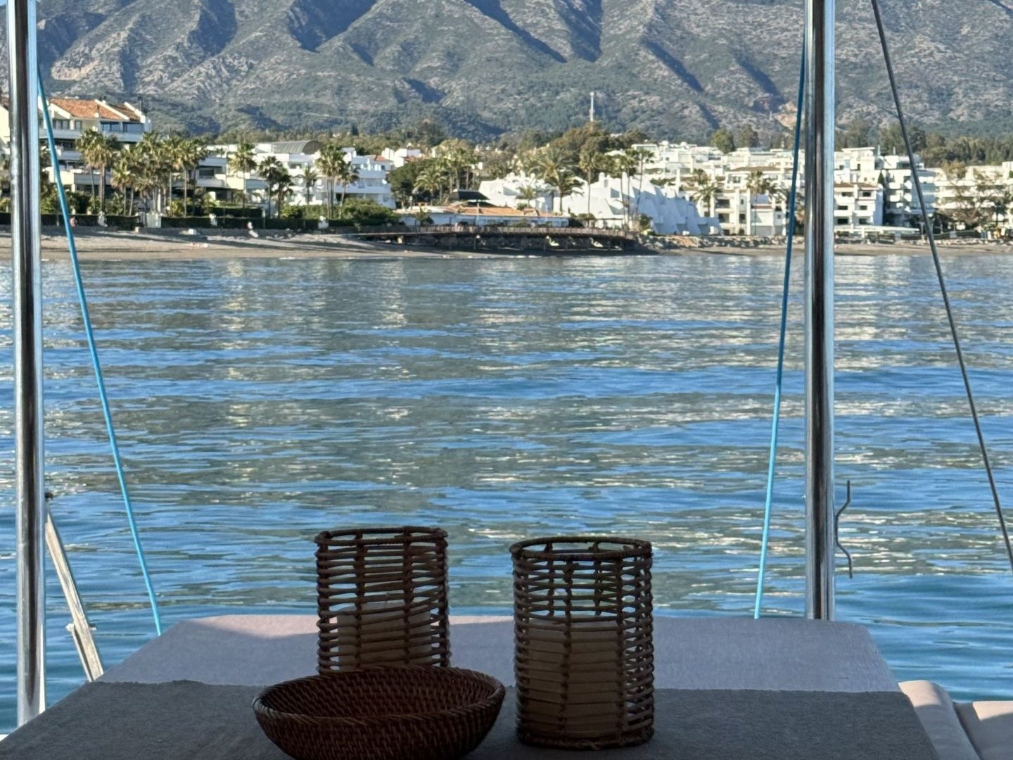 View of a mountain and coastline from a boat with table and decorative items.